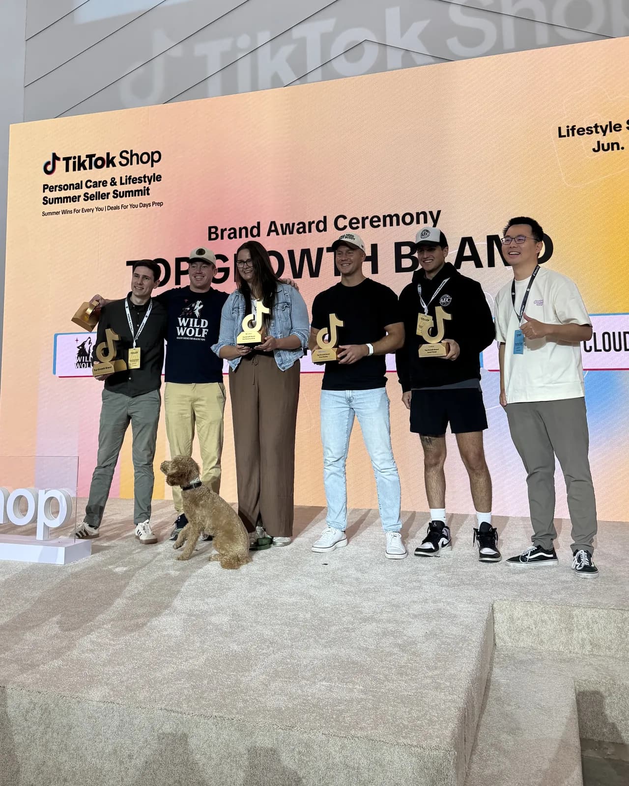On stage at TikTok Shop's Brand Award Ceremony, holding Top Growth Brand trophies
